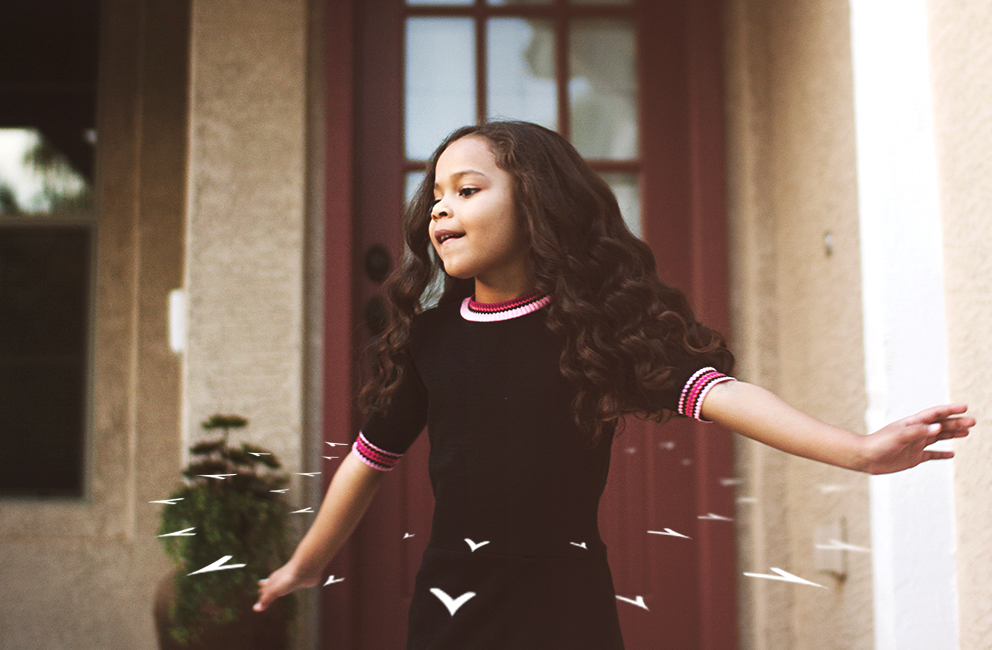 A child, with arms out, in mid twirl.