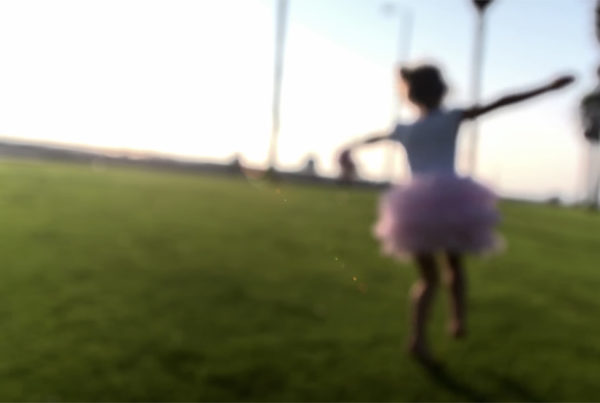 A child wearing a tutu and running in a park.