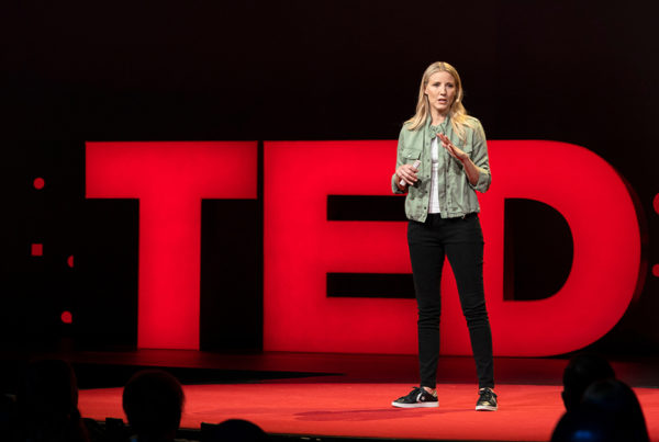 Julie Cordua on stage in front of large lit up letters that spell TED.