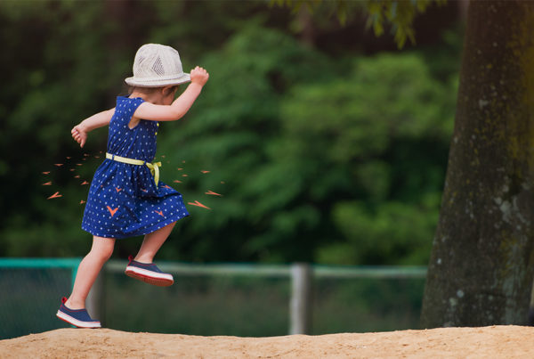Child running in the sand at a playground.