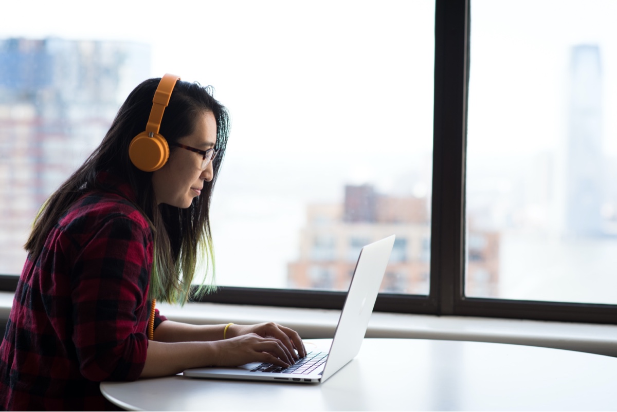 Woman sitting in front of a laptop with headphones on