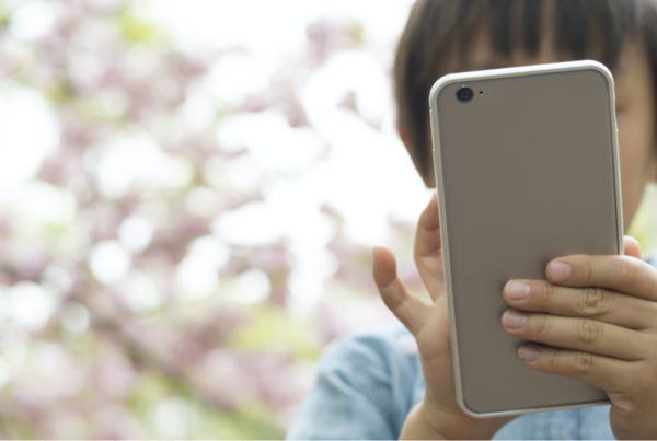 Young child holding a smart phone in front of their face.