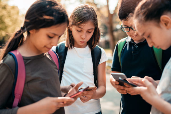School kids using smart phones in schoolyard