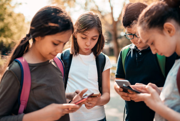 School kids using smart phones in schoolyard