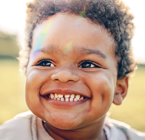 Smiling child with sun shining on their face.