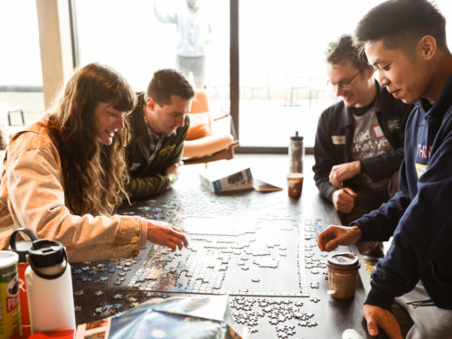 Several employees working on a jigsaw puzzle together.