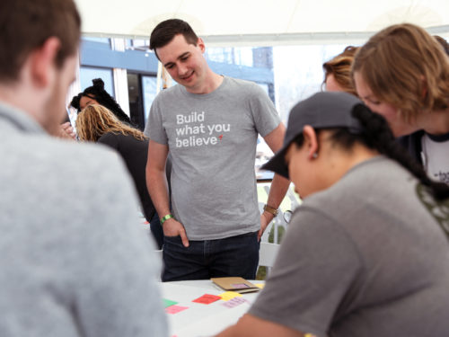 Employees standing around a table during a brainstorming session.