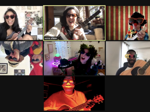 A screenshot of a Zoom meeting featuring employees in costumes and all playing the guitar.