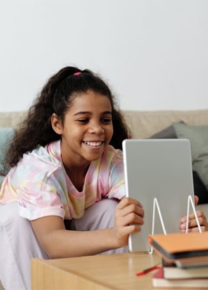 Young girl in tye dye smiles at tablet