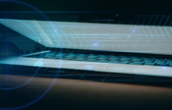 Glow from a partially closed laptop illuminates a dark room.