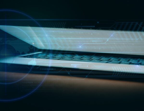 Glow from a partially closed laptop illuminates a dark room.